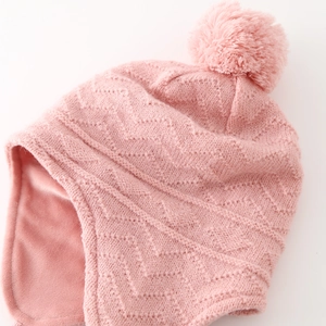 Détail d'un bonnet tricoté rose pour bébé avec doublure polaire et pompon moelleux