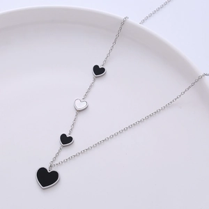 Elegant stainless steel necklace with four black and white heart pendants in offset style