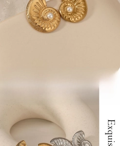 Macro view of French vintage conch earrings with gold textures and pearl details