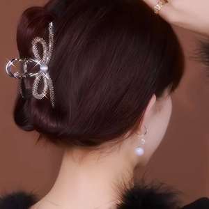 Elegant silver metal hair claw with rhinestone bow and pearl detail on a model's hair
