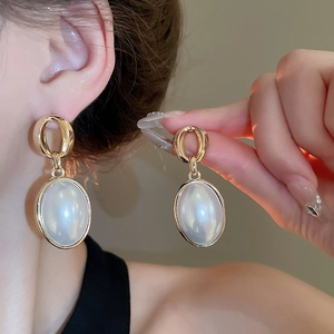 Close-up of vintage French gold oval imitation pearl earrings worn by a model