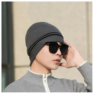Detail of dark gray ribbed knit beanie with black stripes worn by a male model outdoors