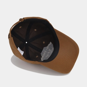 Dettaglio interno del cappellino marrone scuro con fodera, cuciture ed etichetta lavaggio