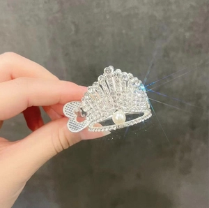 Close-up of a silver crown hair claw clip with sparkling rhinestones and white pearls