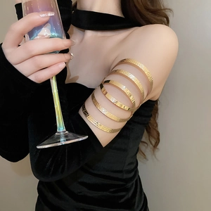 Detail of layered gold arm cuff with mixed hammered and smooth textures on model