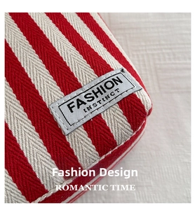 Detail of red and white striped canvas tote with a grey label reading Fashion Instinct