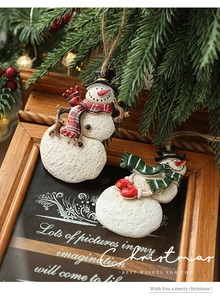 Detail of painted resin snowman ornaments with red and green scarves on a wooden frame