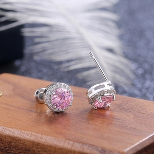 Macro close-up of pink halo stud earrings with round-cut gemstone on a wooden stand