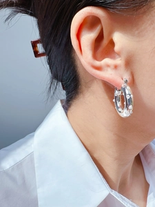 Close-up of polished silver chunky hoop earring with inlaid pearls worn by a model
