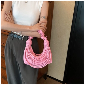 Fashionable pink ruched handbag held by a model in a stylish indoor setting