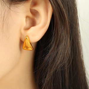 Polished gold triangle titanium steel stud earrings shown on a model's ear lobe