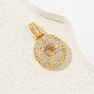 Gold plated letter pendant with zircon stones on a cream textured background