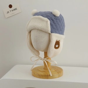 Macro view of light blue quilted pilot hat with white fleece lining and bear embroidery