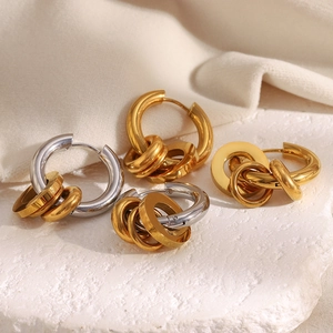 Détail de boucles d'oreilles pendantes à trois anneaux en or et argent sur pierre