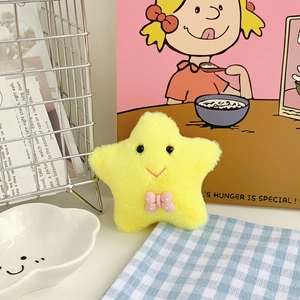 Detailed view of a soft yellow star plush keychain with a pink polka dot bow tie accessory