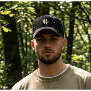 Detail of black washed cotton baseball cap with white polka dots and gold HB metal logo