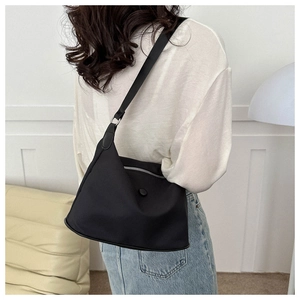 Detail of minimalist black nylon tote bag showing silver zipper and comfortable shoulder strap
