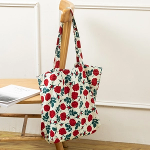 Detail of floral canvas tote bag with red rose pattern hanging on a wooden chair