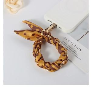 Close-up of brown polka dot silk scarf braided with a gold metal chain phone strap