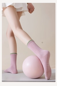 Pink yoga socks with green contrast cuff and anti-slip silicone dots on the sole