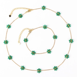 Detail view of woven flower pearl necklace and bracelet set with green crystal floral beads