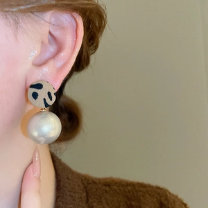 Détail de la boucle d'oreille ronde léopard avec grande perle blanche sur modèle
