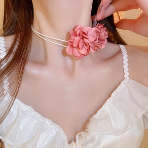 Vue détaillée du ras-du-cou fleur en tissu rose doux avec des pétales superposés