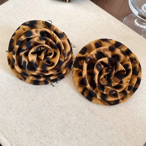 Detailed macro view of fabric leopard print rose shaped earrings with a soft texture