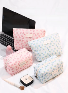 Detailed view of floral lace makeup bags in pink and blue with shell zipper charms