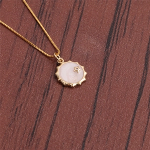 Close-up of golden star disc pendant with pearl inlay on a thin box chain necklace
