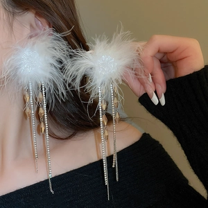 Detail of white feather tassel earrings with sparkling rhinestones worn by a model