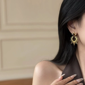 Close-up detail of vintage gold starburst earrings with brown tiger eye stone and crystals