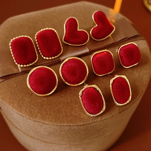 Close-up of four pairs of red velvet and gold geometric earrings on a jewelry box