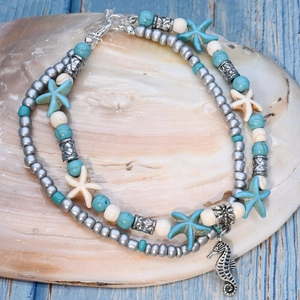 Detail of a layered ocean-themed anklet with starfish and seahorse on a large shell