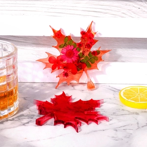 Maple leaf resin coaster featuring embedded dried pink flowers and green leaves