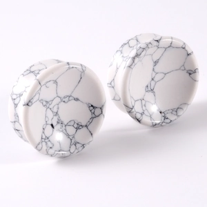 Detail of white turquoise ear gauges with black vein patterns on white background