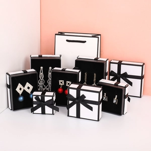 Elegant white jewelry gift box collection with black ribbon bows and matching paper bags