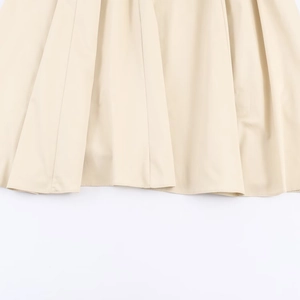 Detailed view of the elegant beige pleated midi dress fabric showing texture and hem
