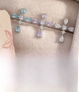 Detailed view of silver cross stud earrings with blue, purple and clear zircon stones