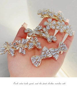 Close-up of sparkling rhinestone flower and bow hair clips on a gold alloy metal base