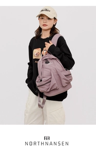 Detail of light purple nylon backpack showing functional pockets and drawstring side pouch