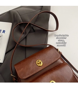 Detailed close-up of dark brown textured leather flap bag with gold twist lock