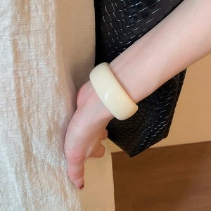 Gros plan d'un bracelet manchette en acrylique blanc cassé au design minimaliste et chic
