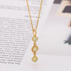 Elegant gold S925 silver necklace with three oval green prehnite stones on a book