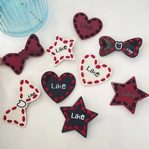 Detail of heart, star, and bow hair clips with Like text in red, black, and white colors