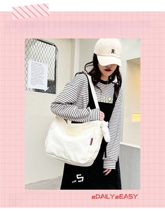 Side view of a white canvas tote bag showing the red label and large capacity on a model