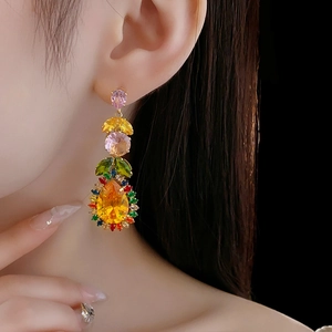 Close-up of model wearing gold leaf drop earrings with colorful zircon gemstones