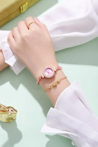 Close-up of elegant pink dial watch and gold bangle set on a female model wrist