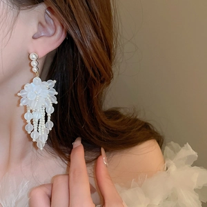Eleganti orecchini bianchi a fiore con nappe di perle indossati da una modella