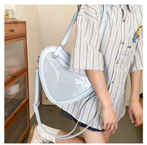 Side view of heart-shaped blue JK ita bag with mesh window worn by a model